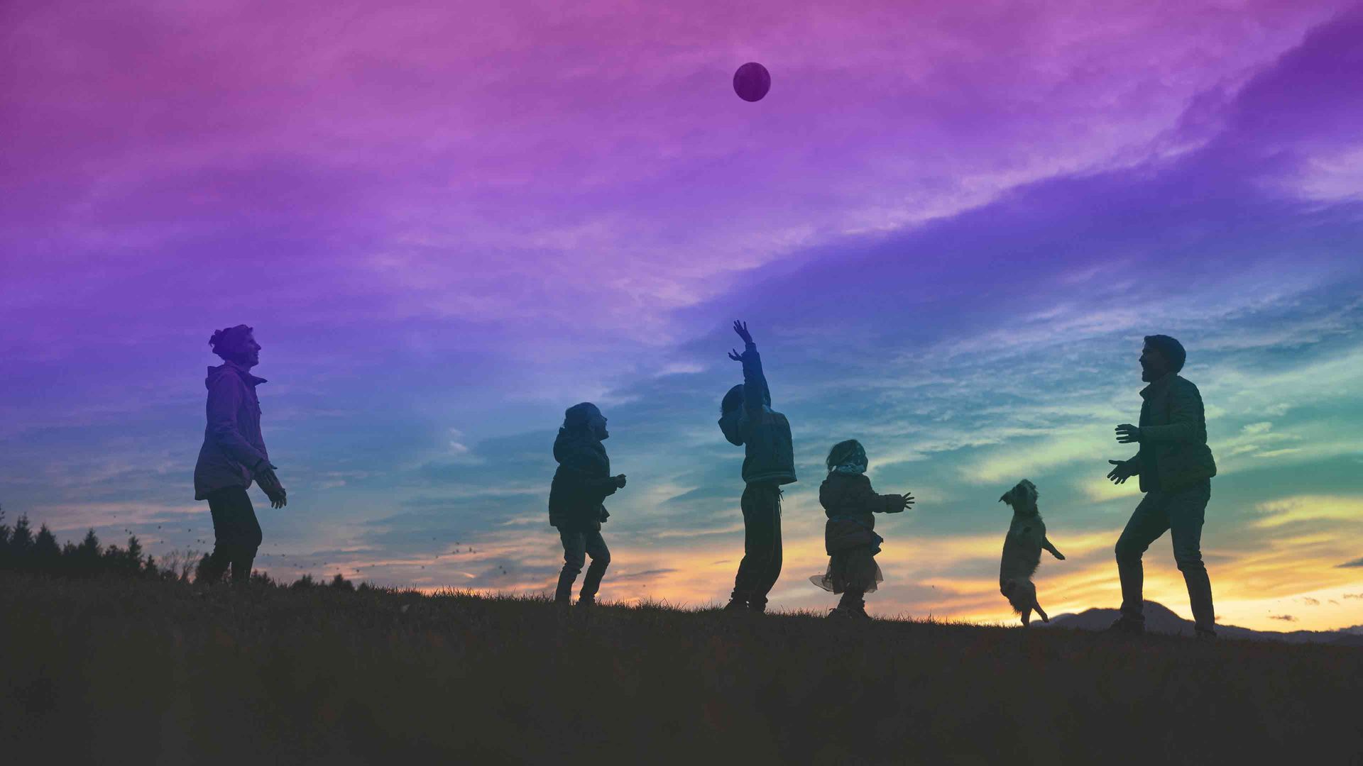 silhouette of a family playing and having fun outdoors at sunset