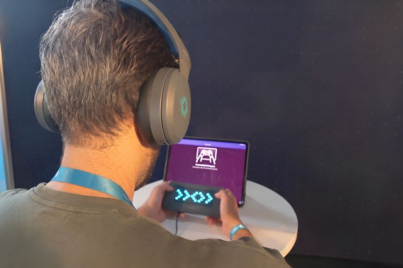 A person wearing the Sens.ai headset runs a BrainYears assessment, holding the GeniusPulse controller against the branded BrainYears backdrop.